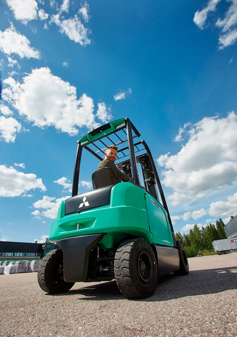 Chauffør kører gaffeltruck fra Logisnext Denmark udendørs med blå himmel i baggrunden