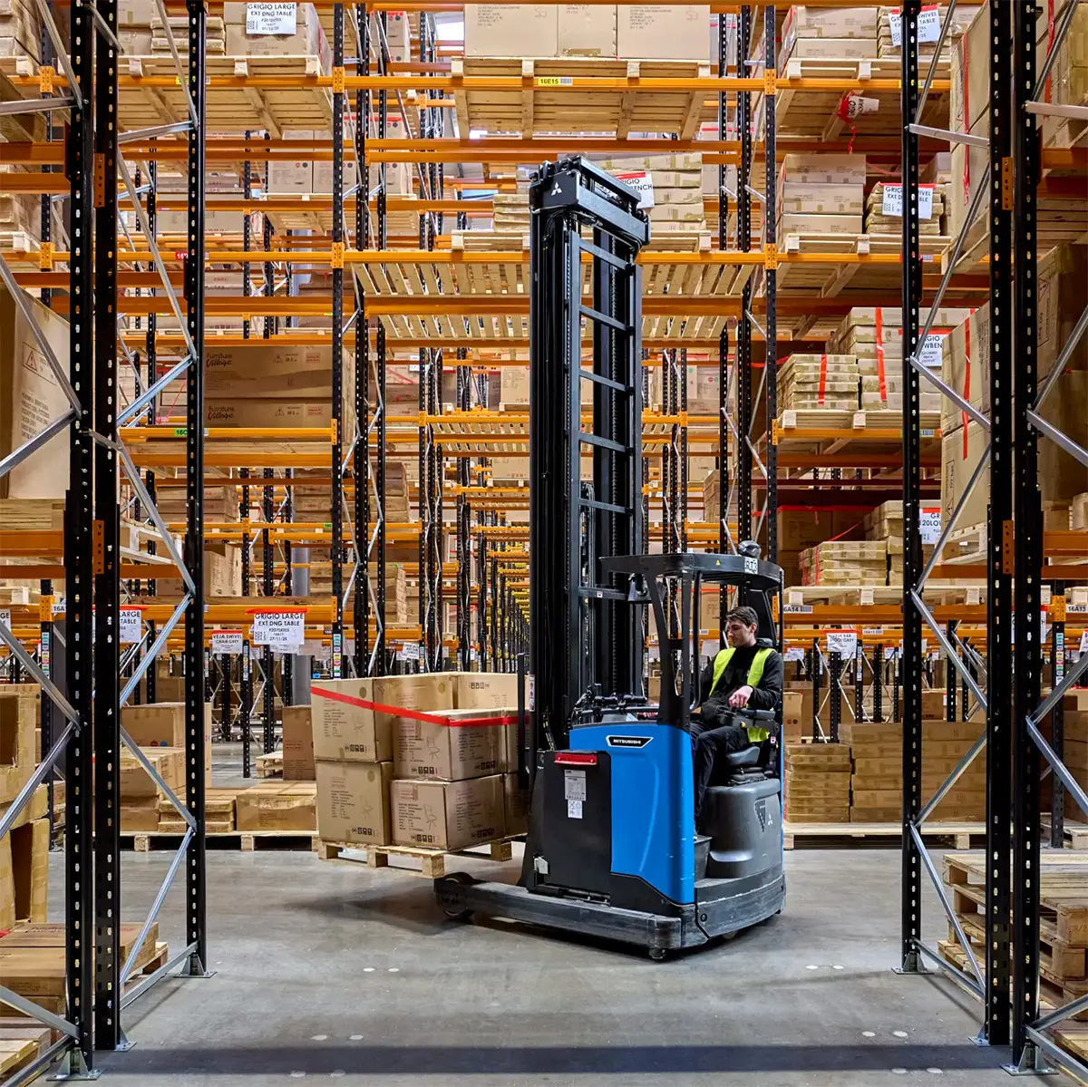 Medarbejder kører reachtruck fra Logisnext Denmark mellem højlagerreoler med paller