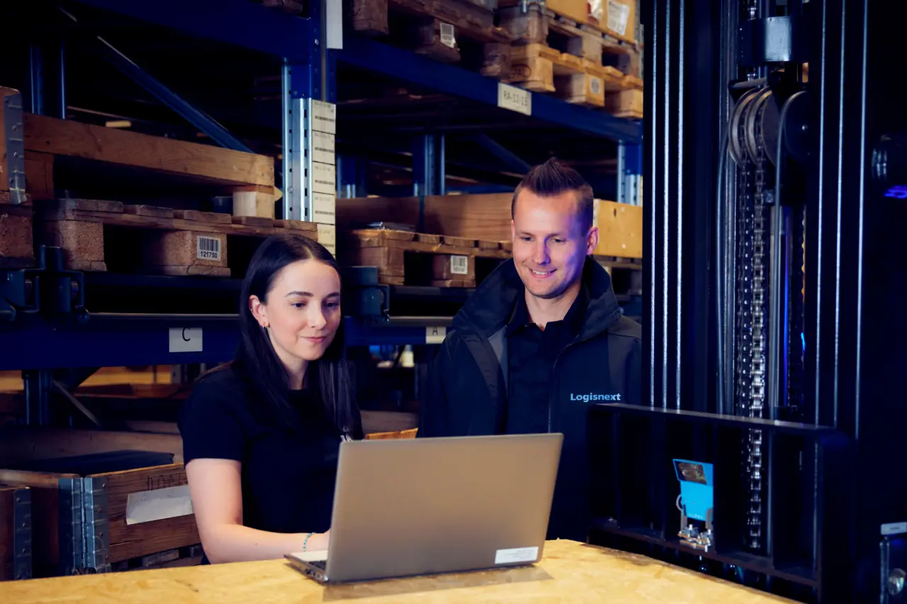 Medarbejdere fra Logisnext Denmark ser på bærbar computer i lager ved smalgangstruck