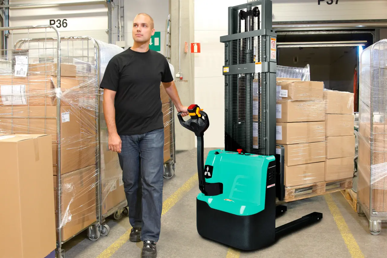 Medarbejder fører Essential-stacker fra Logisnext Denmark med palle mellem lagerreoler