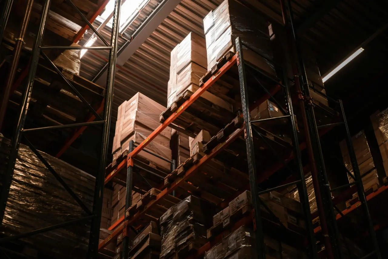 Højlagerreol med palleteret gods set nedefra i dramatisk lys – intralogistisk opbevaring hos Logisnext Denmark