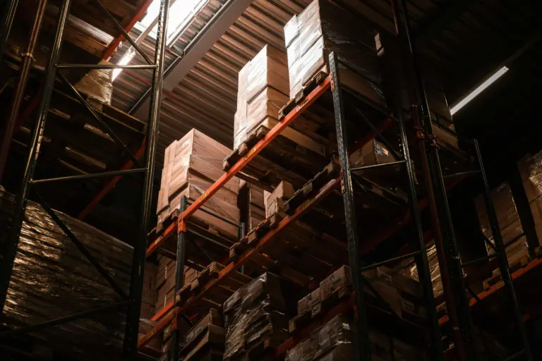 Højlagerreol med palleteret gods set nedefra i dramatisk lys – intralogistisk opbevaring hos Logisnext Denmark