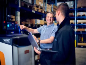 Konsulenter fra Logisnext Denmark konfigurerer Rocla AGV-truck med bærbar computer i lager