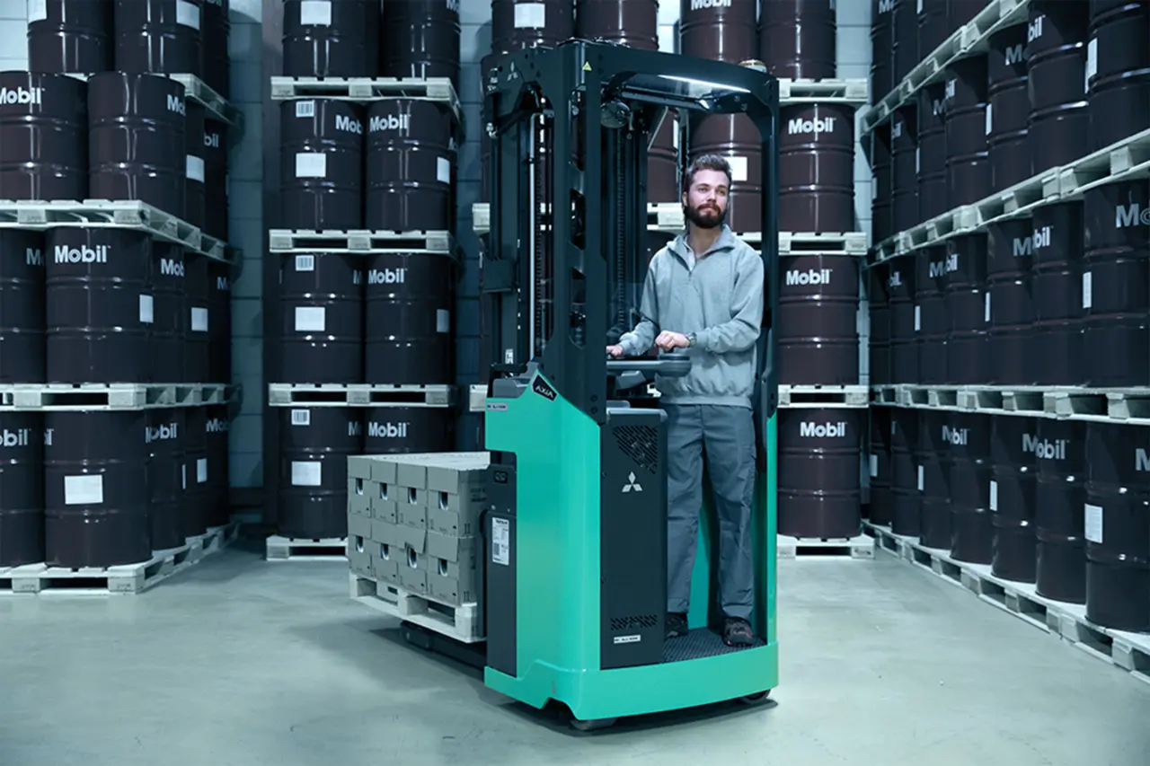 Medarbejder kører AXIA-reachtruck fra Logisnext Denmark med palle mellem Mobil-olietønder