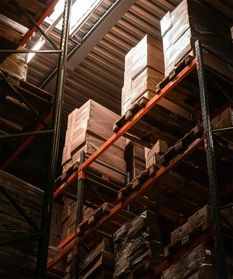 Højlagerreol med palleteret gods set nedefra i dramatisk lys – intralogistisk opbevaring hos Logisnext Denmark