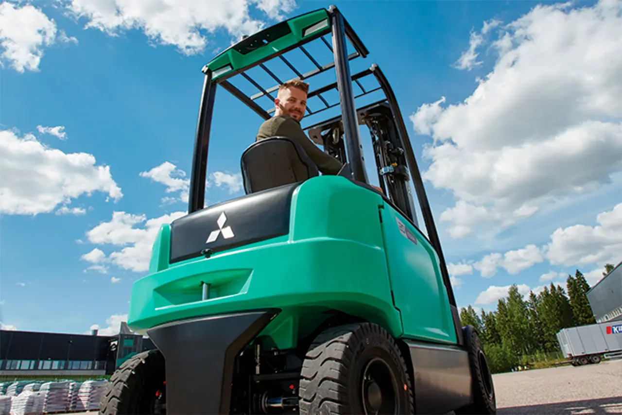 Chauffør kører gaffeltruck fra Logisnext Denmark udendørs med blå himmel i baggrunden